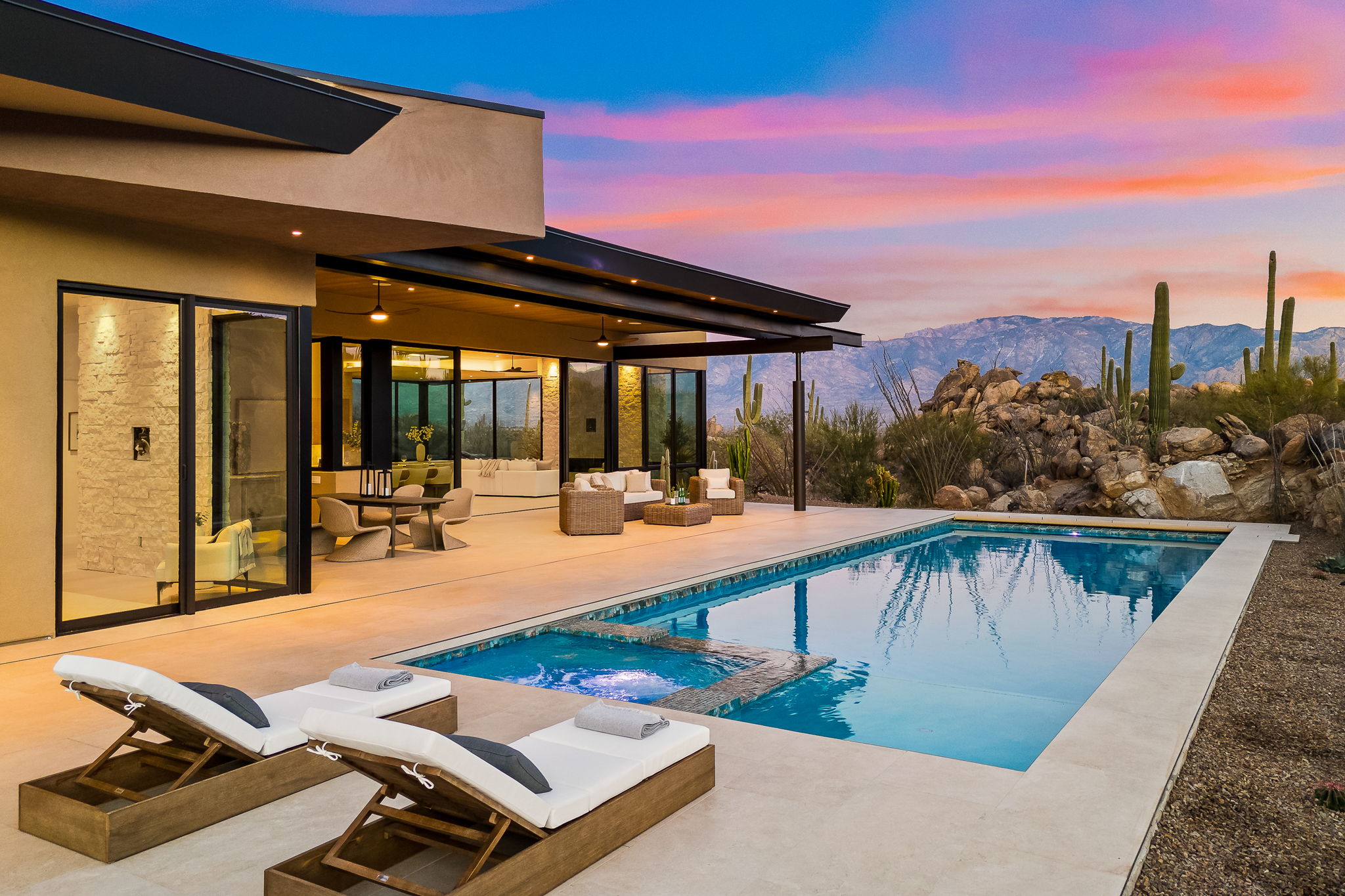 Contemporary desert home with pool and patio at sunset with mountain views
